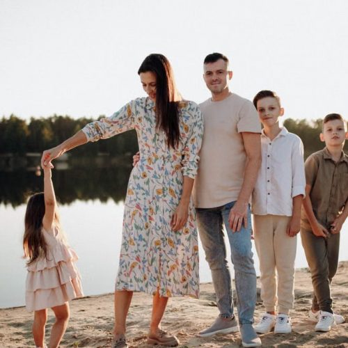 A family of five enjoys a serene lakeside vacation at sunset, capturing precious moments together.